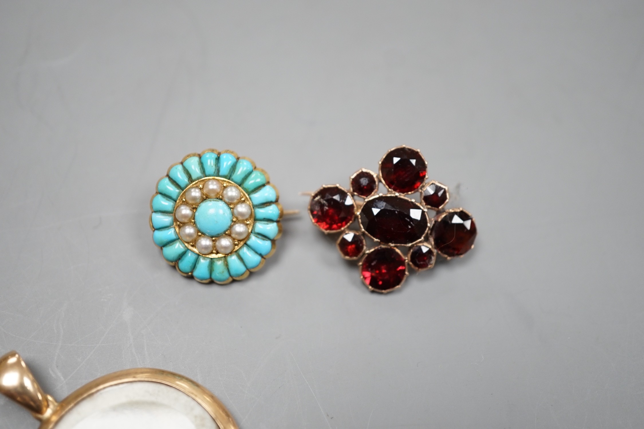 A Victorian yellow metal, turquoise and split pearl set circular brooch, 19mm, a similar garnet set brooch and a 15ct mounted miniature portrait pendant.